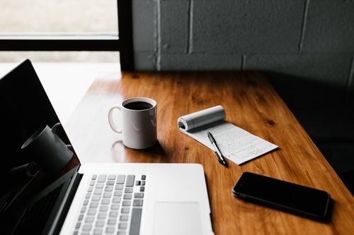 laptop, notepad, mobile phone and coffee on the desktop